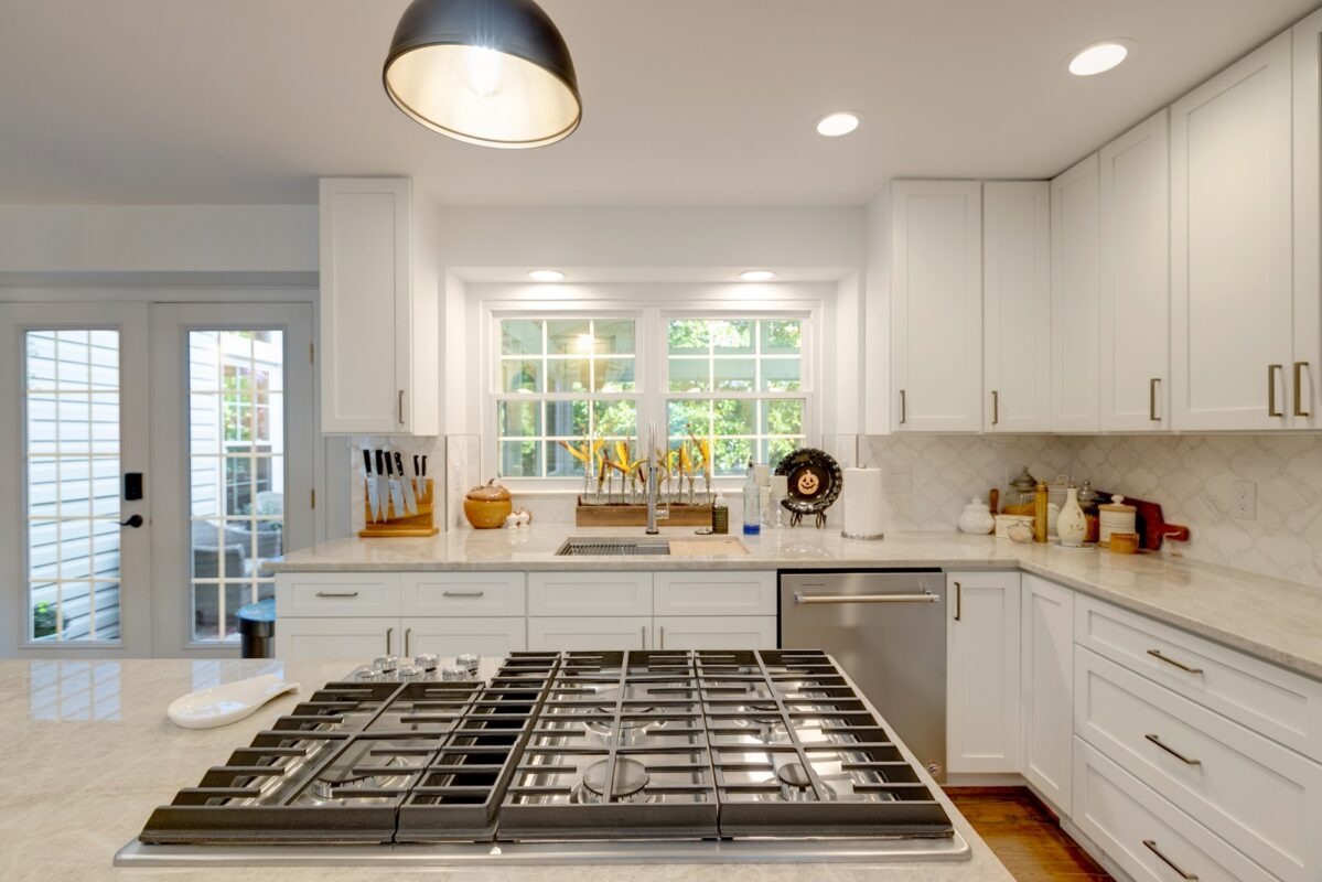 Gas cooktop island facing a white kitchen with French doors
